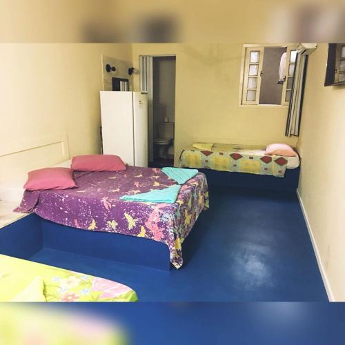 a room with two beds and a refrigerator at Pousada Gran Gaviota in Cabo Frio