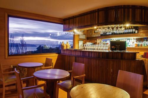 a restaurant with two tables and a bar with a view at Hotel Parque Quilquico in Castro