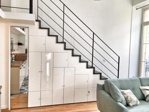 - un escalier dans le salon doté d'un canapé bleu dans l'établissement Homelivia, Appart FRIDA, mezzanine, déco raffinée et balcon, à Nice