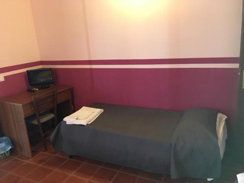 ein kleines Schlafzimmer mit einem Bett und einem TV in der Unterkunft Porta Pantalica in Ferla