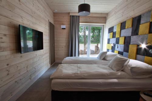 a bedroom with two beds and a flat screen tv at Stranda in Giżycko