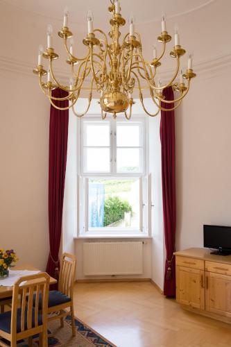 a dining room with a chandelier in front of a window at Schloss Gumpoldskirchen in Gumpoldskirchen