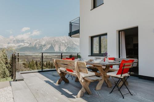 a wooden table and chairs on a patio with mountains at Appartements Almnest in Schladming