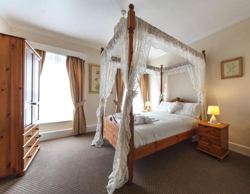 a bedroom with a canopy bed and a window at Bacchus Hotel in Sutton on Sea