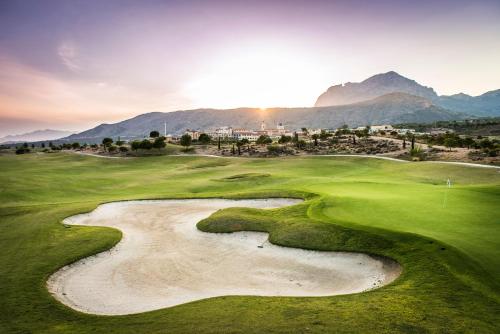 a view of a golf course with mountains in the background at The Level at Meliá Villaitana in Benidorm