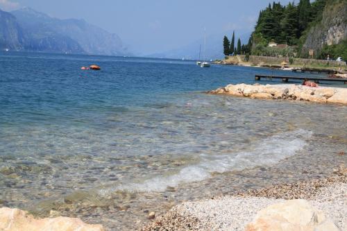 a body of water with a rocky shore with boats at Albergo Del Garda in Torri del Benaco