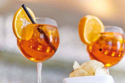 two wine glasses with orange slices on a table at Albergo Del Garda in Torri del Benaco