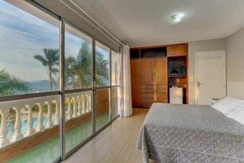 um quarto com uma cama e uma grande janela em Canasvieiras Hotel em Florianópolis