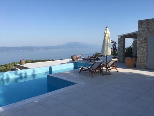 a swimming pool with a table and umbrella and chairs at Villa Salina Luxury Pool Villa in Kechria