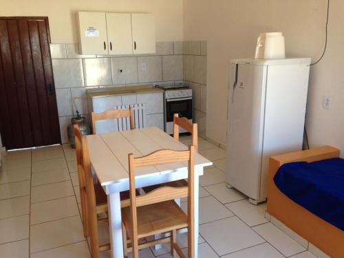 a kitchen with a table and a white refrigerator at Garopaba Praia Club in Camacho