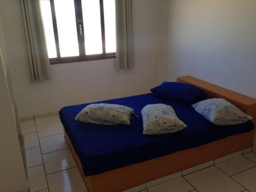 a bedroom with a bed with blue sheets and a window at Garopaba Praia Club in Camacho