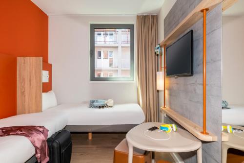 a hotel room with two beds and a tv at ibis budget Gent Centrum Dampoort in Ghent