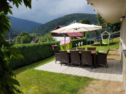 a patio with a table and chairs and an umbrella at Ubytování v soukromí - U Hlinků in Horní Maršov