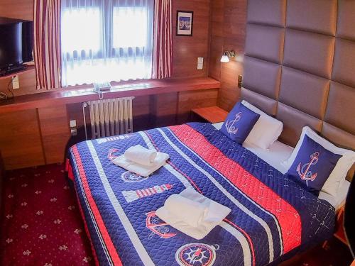 ein Schlafzimmer mit einem Bett mit einer blauen und roten Decke in der Unterkunft Botel Albatros in Prag
