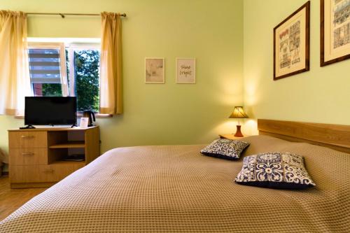 una camera da letto con un letto con due cuscini e una televisione di Vila Estate a Palanga