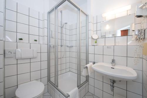 a bathroom with a shower and a toilet and a sink at Comfort Garni Stadtzentrum Hotel in Bielefeld
