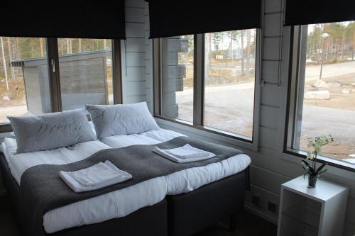 Cama en habitación con sofá y ventanas en Naava Chalet Pyry (201), en Ähtäri