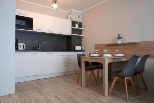 コウォブジェクにあるCHILLIapartamenty - Bliżej Morza - DREAMの白いキャビネット、木製テーブルと椅子付きのキッチンが備わります。
