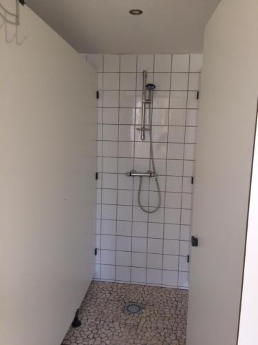 une salle de bain avec douche carrelée de blanc dans l'établissement les roulottes de l'airou, à Beauchamps