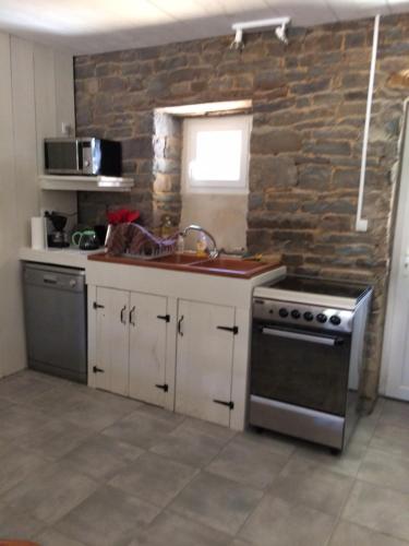 Il comprend une cuisine avec une cuisinière et un mur en pierre. dans l'établissement les roulottes de l'airou, à Beauchamps