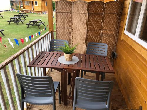a wooden table and chairs on a porch with a potted plant at Bacchus Hotel Log Cabins in Sutton on Sea
