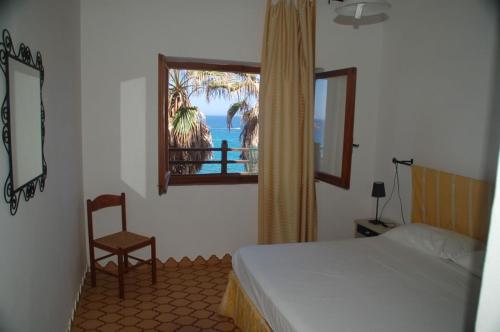 Un dormitorio con una cama y una ventana y una silla. en Waterfront Apartments Bosa Porto Alabe, en Porto Alabe
