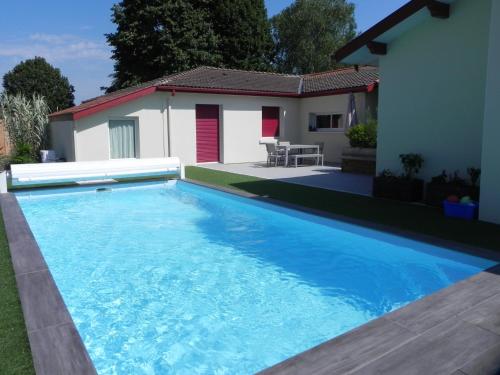 une grande piscine bleue devant une maison dans l'établissement La clé de vos Rêves, à Orthevielle