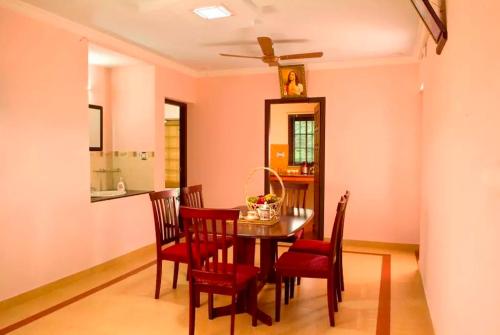 ein Esszimmer mit einem Tisch und roten Stühlen in der Unterkunft Villa Brook Heritage Home in Alappuzha