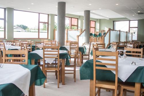 ein Esszimmer mit Tischen und Stühlen sowie grünen Tischdecken in der Unterkunft O Vendaval Hostal Restaurante in Barreiros