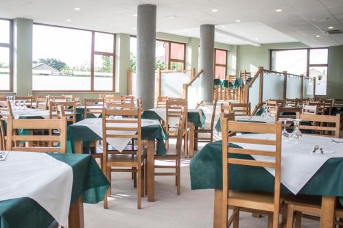 jadalnia ze stołami i krzesłami z zielonymi obrusami w obiekcie O Vendaval Hostal Restaurante w mieście Barreiros