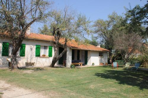 une maison blanche avec des volets verts et une cour dans l'établissement Les Mazets du Paty, à Albaron