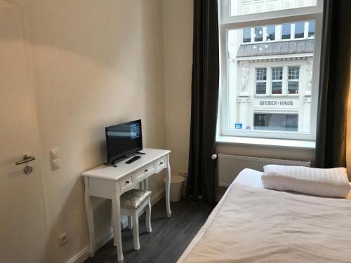 a bedroom with a bed and a desk with a television at Hotel Fame am Hauptbahnhof in Hamburg