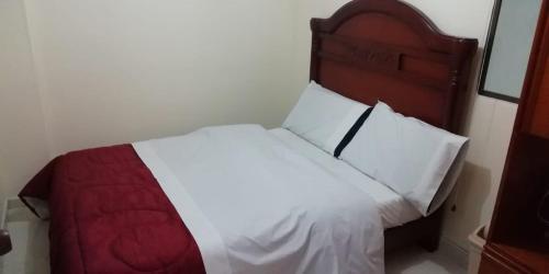 - une chambre avec un lit blanc et une tête de lit en bois dans l'établissement Hostal Fontanar Prado, à Bogotá