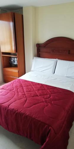 Un dormitorio con una cama con una manta roja. en Hostal Fontanar Prado, en Bogotá