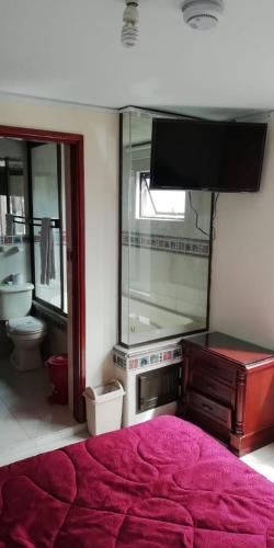 - une chambre avec un grand lit rouge et une télévision dans l'établissement Hostal Fontanar Prado, à Bogotá
