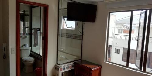 La salle de bains est pourvue de toilettes, d'une télévision et d'une fenêtre. dans l'établissement Hostal Fontanar Prado, à Bogotá