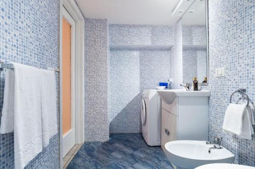 uma casa de banho em azulejos azuis com um lavatório e um WC em Appartamento Chicca em Sperlonga