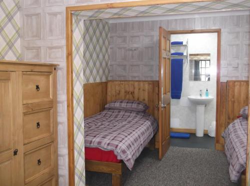 a small bedroom with a bed and a sink at The Steading Highland Glen Lodge in Drumnadrochit