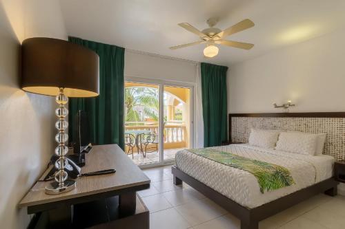 a bedroom with a bed and a table with a lamp at Hotel Villa Taina in Cabarete