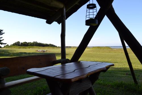 a wooden bench sitting on a porch with a view of a field at Ungru Holiday Houses in Suuresadama