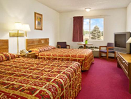 a hotel room with two beds and a flat screen tv at Westwood Inn & Suites - Kimball in Kimball
