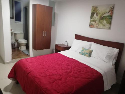 1 dormitorio con cama roja y blanca y aseo en Hotel Fontanar Corferias, en Bogotá