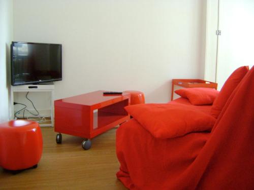 ein Wohnzimmer mit einem roten Sofa und einem Fernseher in der Unterkunft le corsaire in Granville