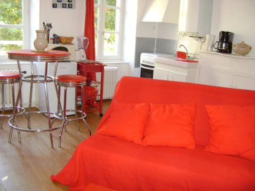 ein Wohnzimmer mit einem roten Sofa und einer Küche in der Unterkunft le corsaire in Granville