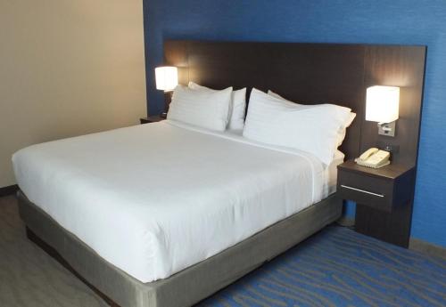 a large bed in a hotel room with a phone at Holiday Inn Hotel & Suites Regina, an IHG Hotel in Regina
