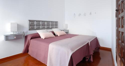 een slaapkamer met een groot bed met roze lakens en kussens bij El 5 de la Hoguera in Córdoba