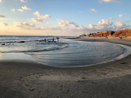 a beach with people standing in the water at Caravans through the nature in Mikhmoret