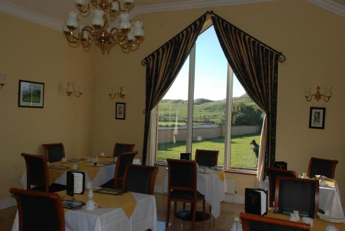 a dining room with tables and a large window at The 19th Golf Lodge in Ballybunion