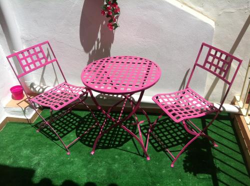 2 rosa Stühle und ein Tisch auf dem Balkon in der Unterkunft NERJA APARTAMENTO TURISTICO 2B in Nerja