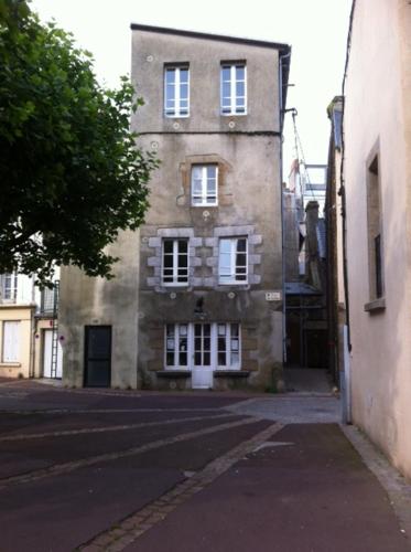 ein altes Backsteingebäude mit weißen Fenstern auf einer Straße in der Unterkunft le flibustier in Granville